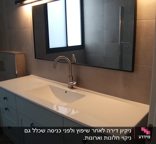 כיור לבן עם ברז מתכת, מראה גדולה ותאורה